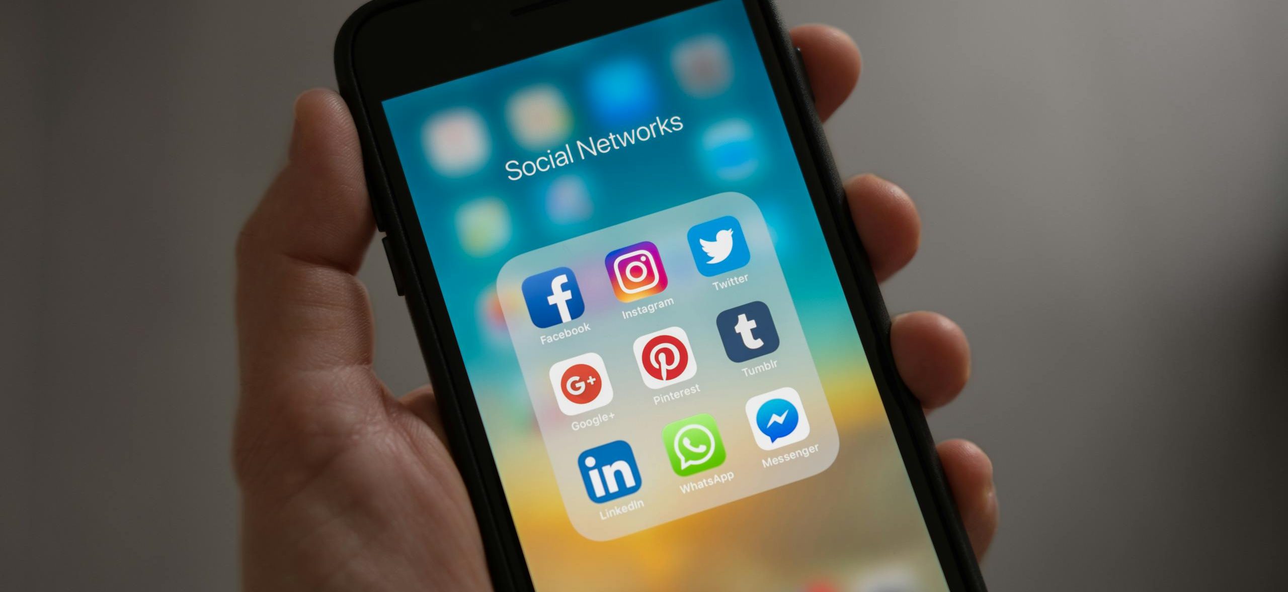 A smartphone displaying various social media icons held in a hand, showcasing modern communication apps.